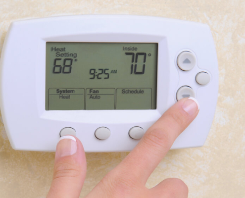 white-home-thermostat-with-hand-making-changes-OBoys-Heating-And-Air-thermostat-temperature-setting-in-the-summer