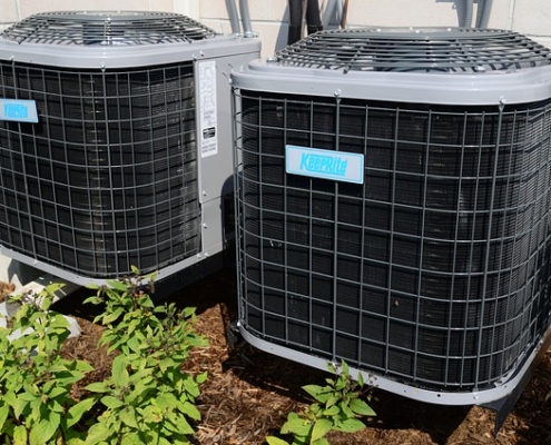 two-air-conditioner-units-outside-by-a-bush-Oboys-ac-system-maintenance-guide