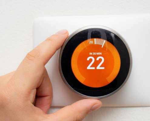 hand-adjusting-smart-thermostat-oboys-heating-and-air-benefits-of-using-a-smart-thermostat
